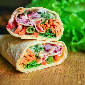 Frisch und bunt: Karotten, rote Zwiebelm Peperoni und Salate, mit Dip, eingrollt in einem Wrap 